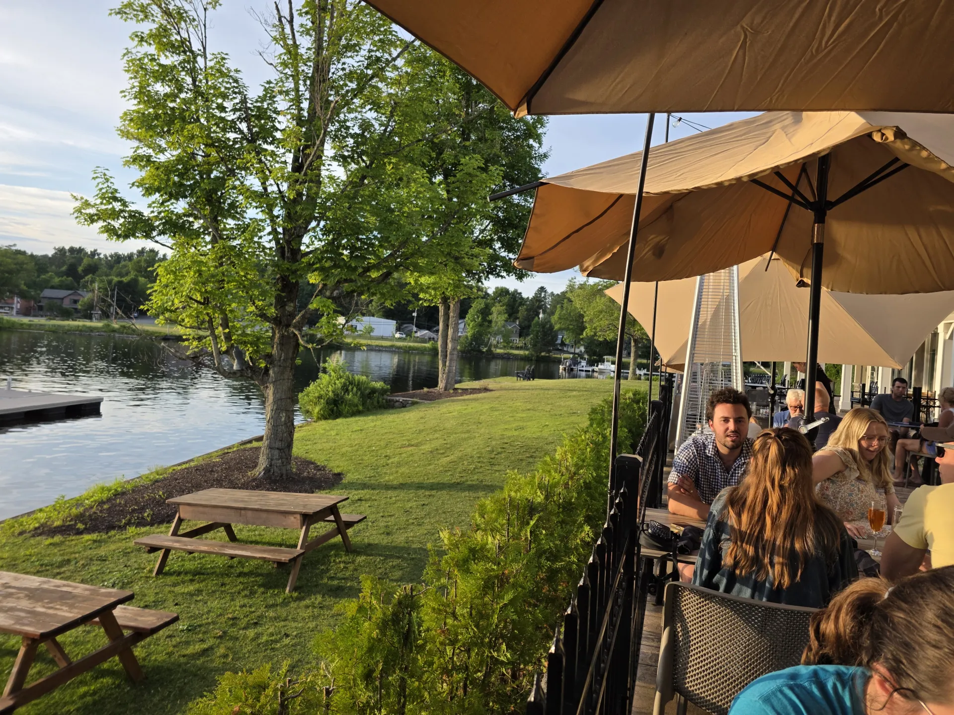The dining patio next to a swath of grass with picnic tables and the waterfront of Lake Flower