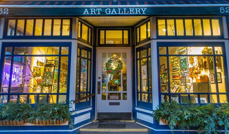 Exterior of the Adirondack Artists Guild gallery with its large storefront windows lit up from the inside