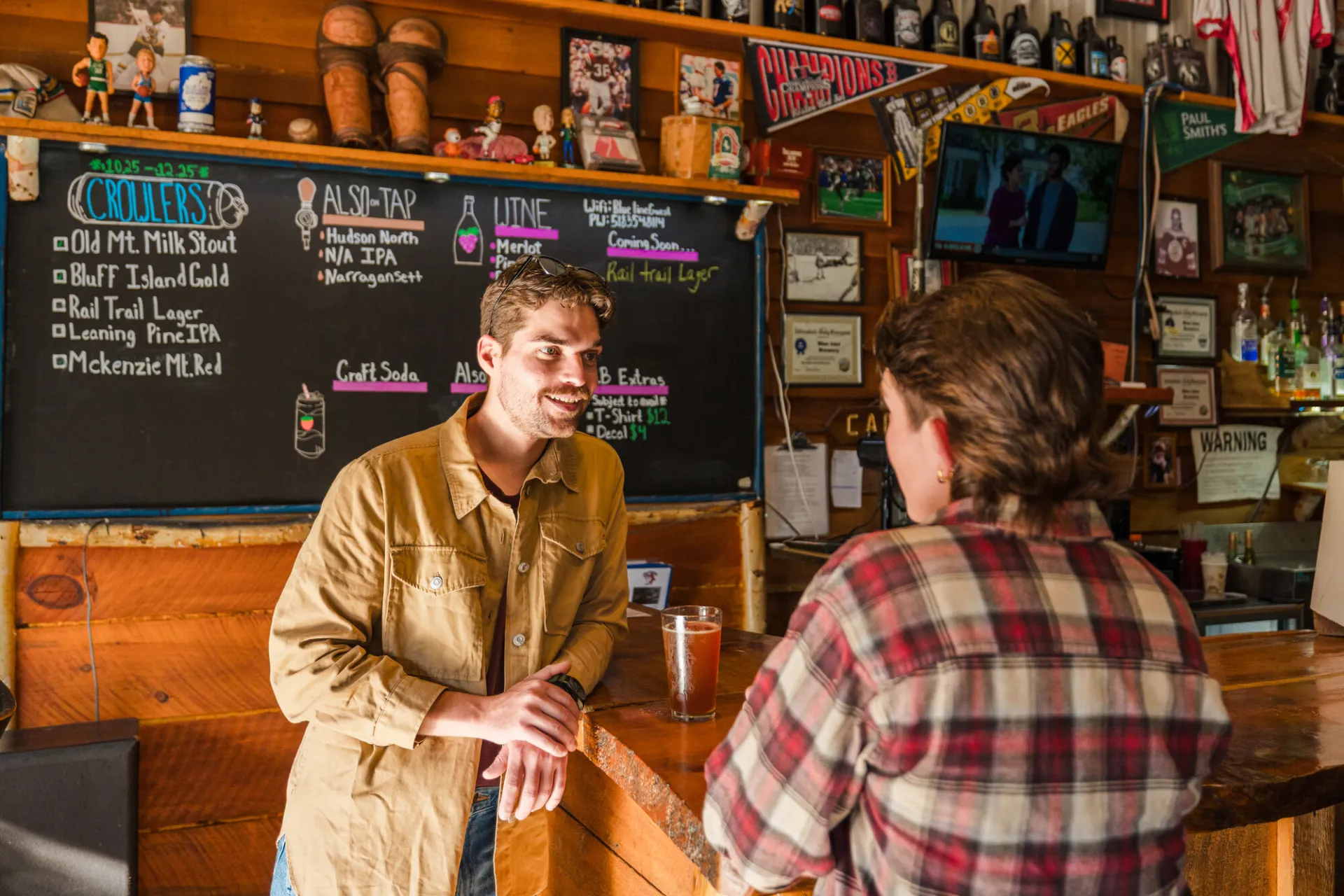 A man and woman talk at a rustic bar.
