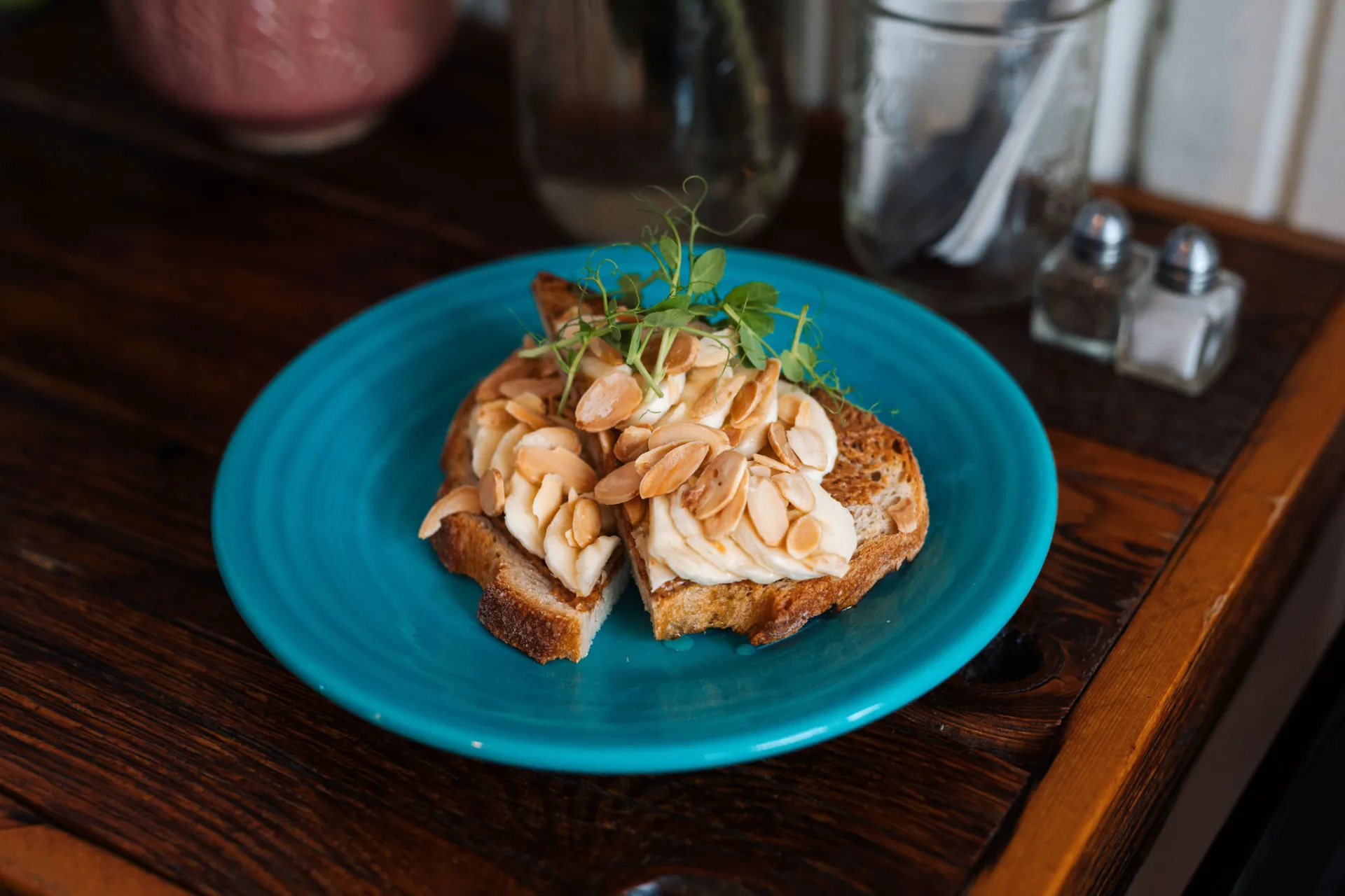 Sliced banana and peanuts on toast on a blue plate.