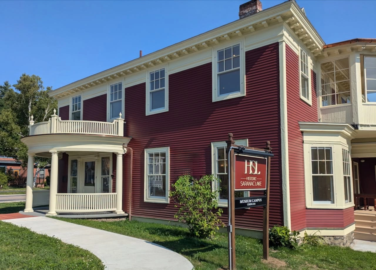 The exterior of a red and white historic home museum on a sunny day.