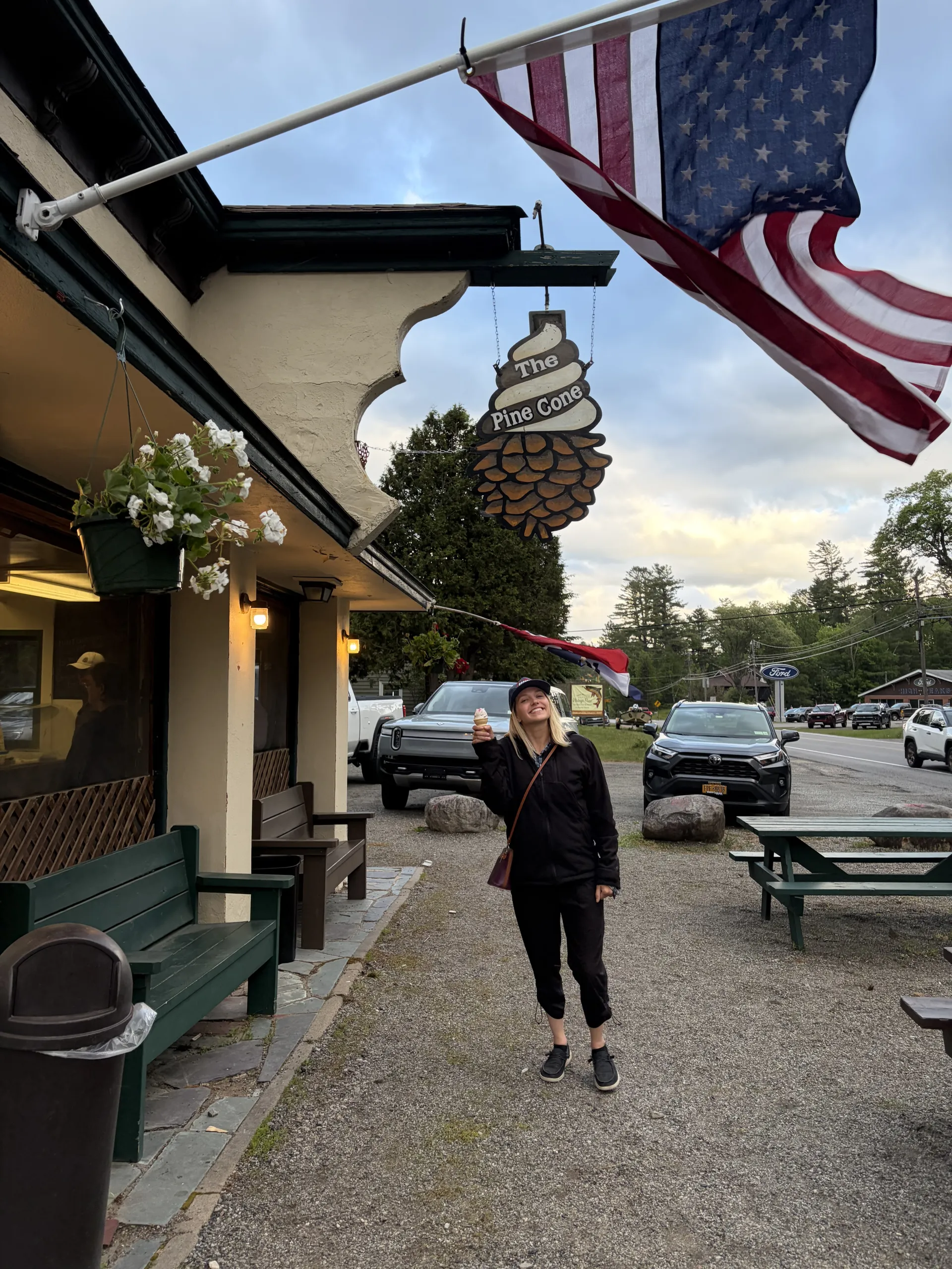 A woman poses in front of an ice cream stand near sunset.