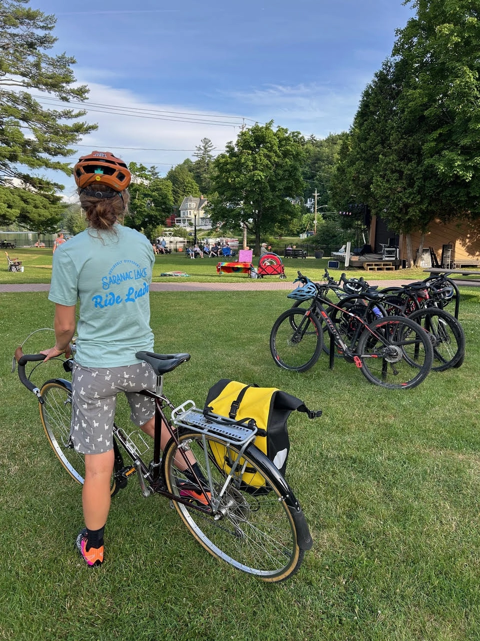 the back of a person on a bicycle at a park with other bikes parked nearby
