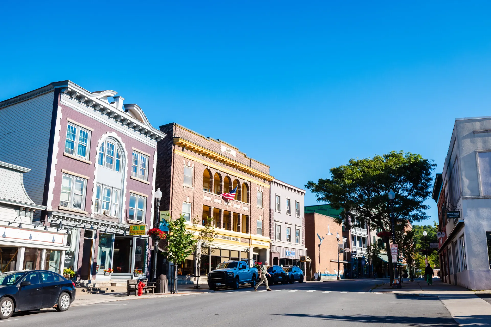A row of historic brick shopfronts on a small town street on a sunny summer day.