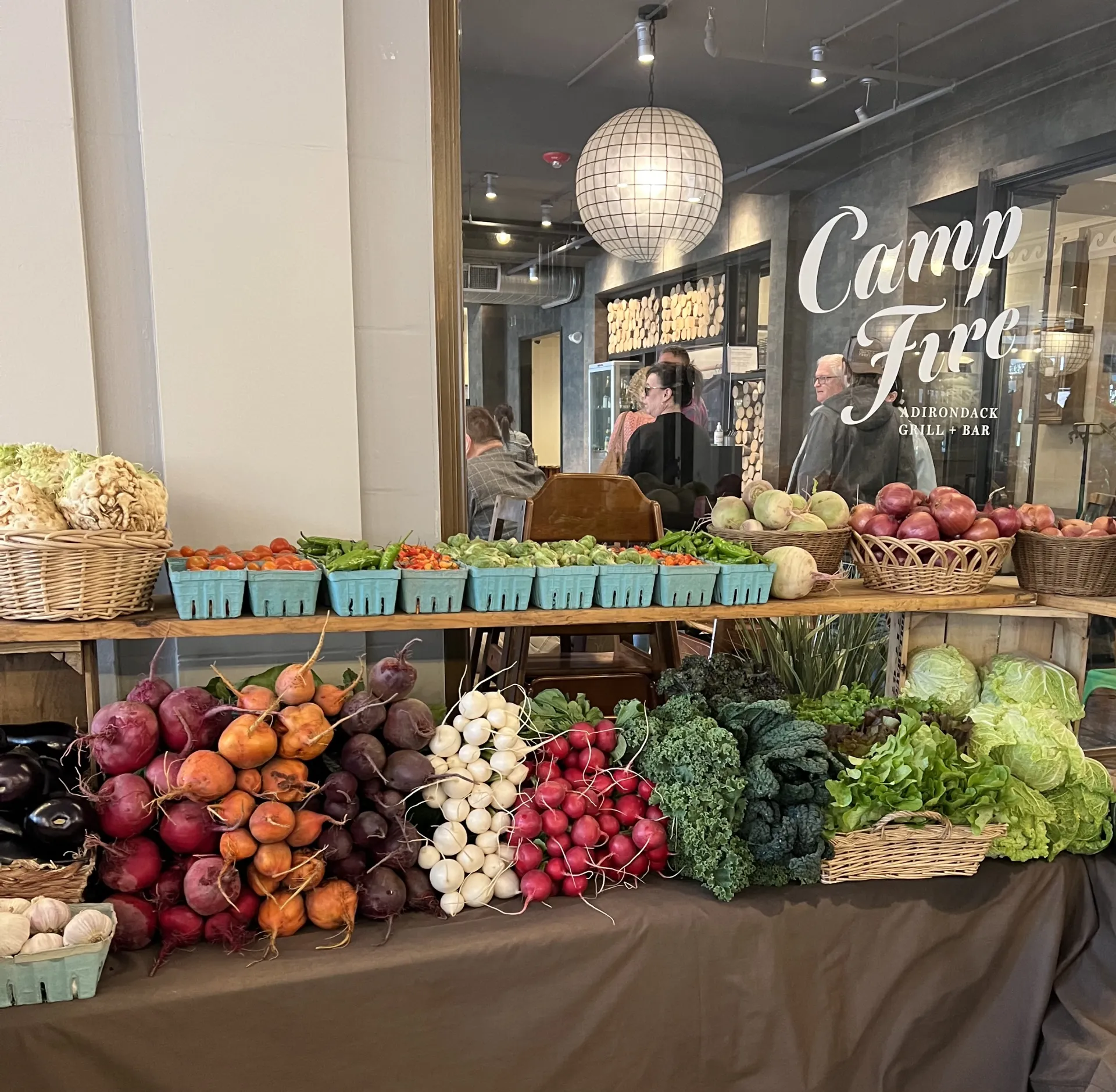 A table at an indoor farmers market filled with fresh produce. 