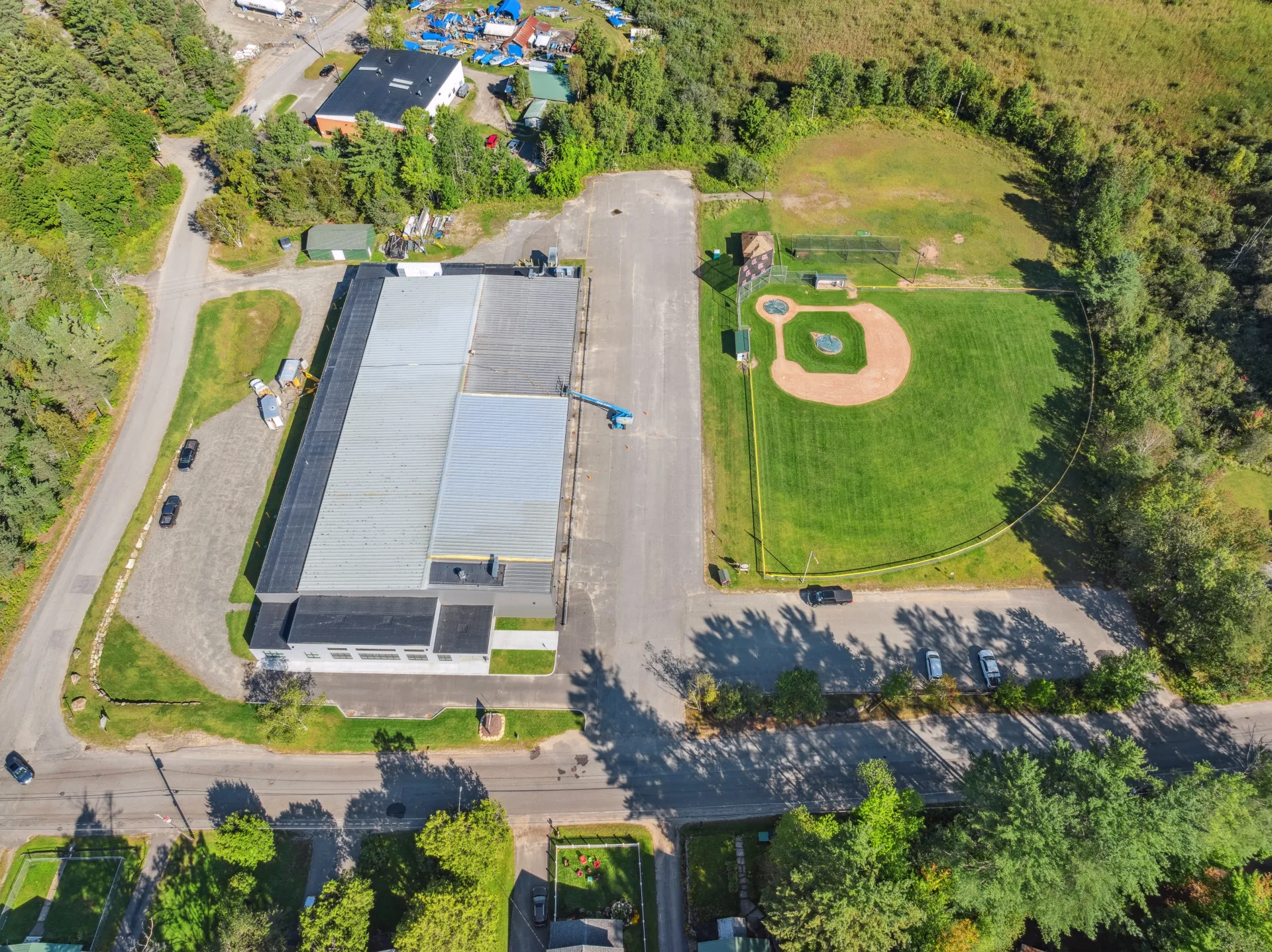 An aerial view of the top of the Saranac Lake Civic Center next to a baseball diamond.