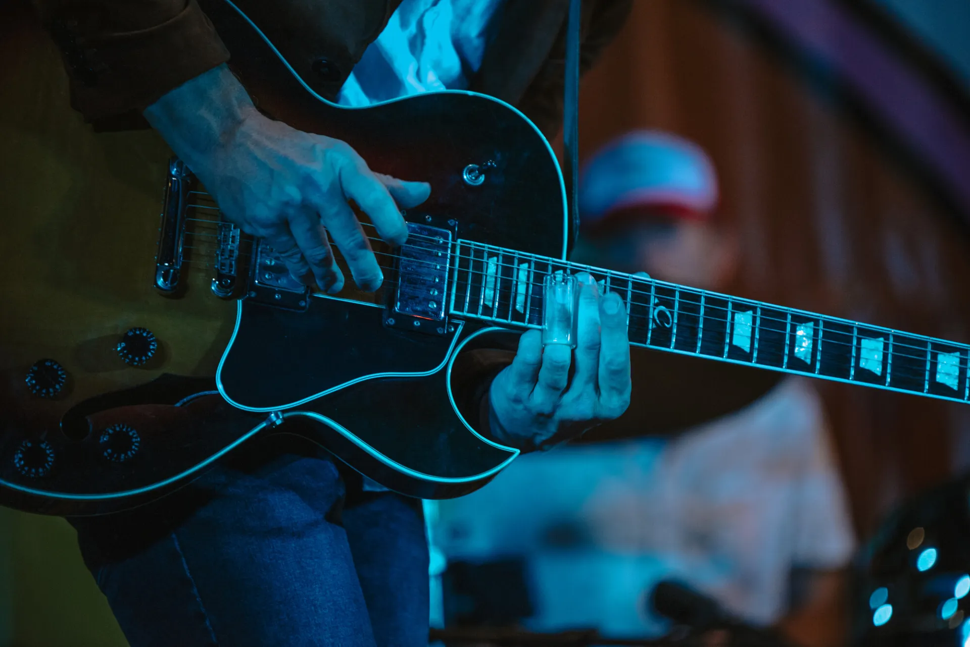 A person playing guitar at a live music concert in Saranac Lake.