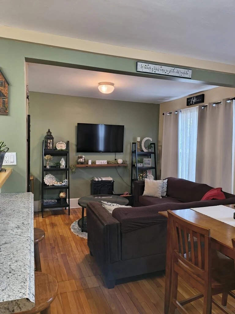 A green living room with wood floors and trim.