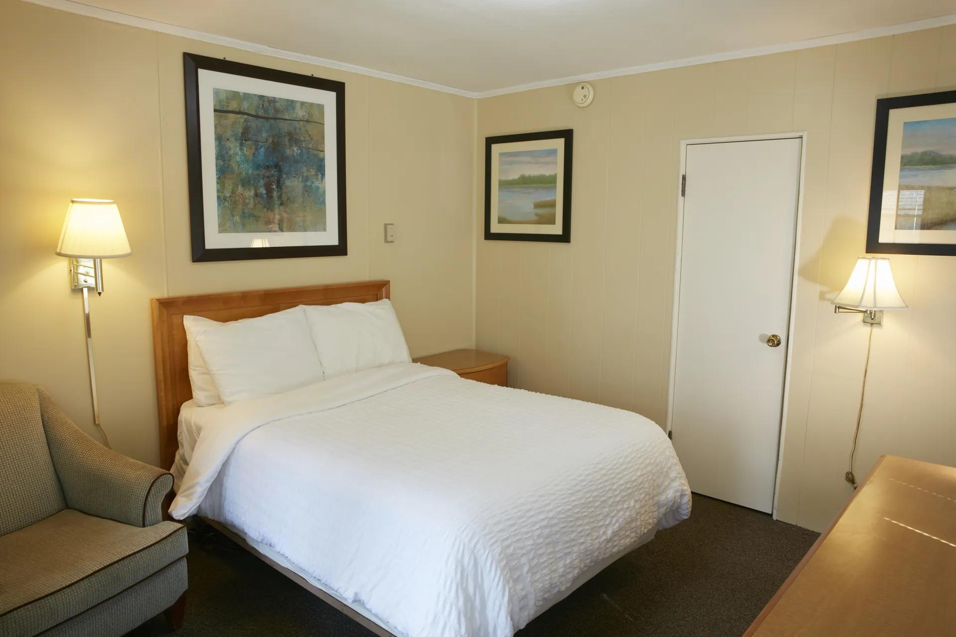 Plush white linens on a queen bed in a yellow walled room at The Ashley.