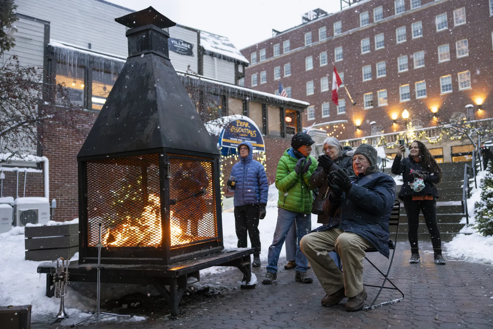 People gather around an outdoor fireplace in winter. 