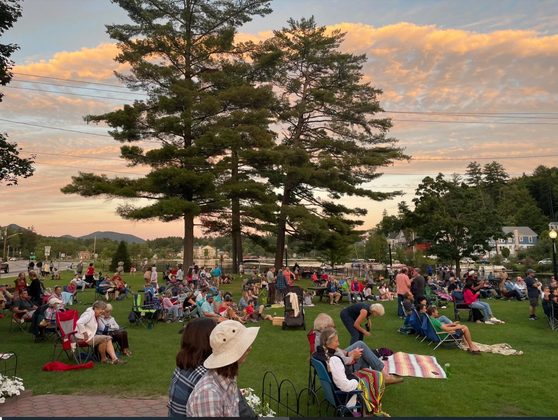 outdoor music concert with lake in the background as the sun goes down 