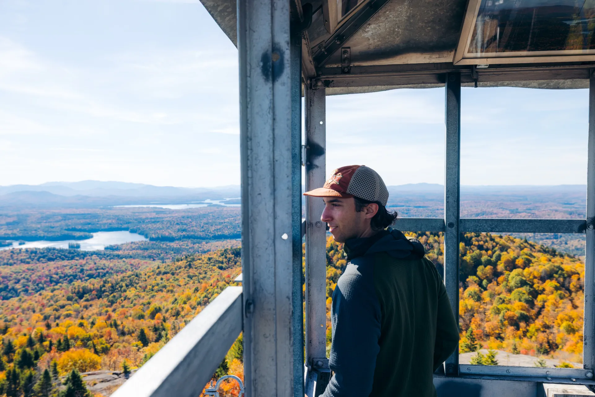 A man looks out from a fire tower in fall. 