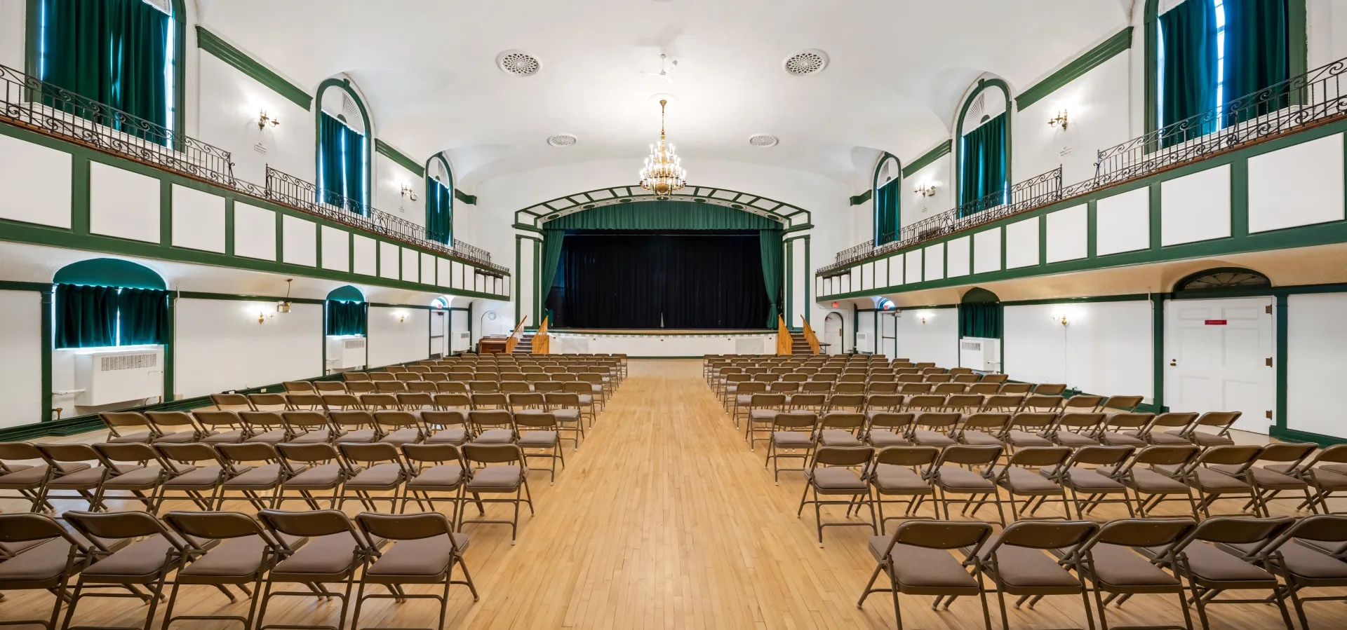 The auditorium with balconies and raised, curtained stage at the Harrietstown Town Hall.