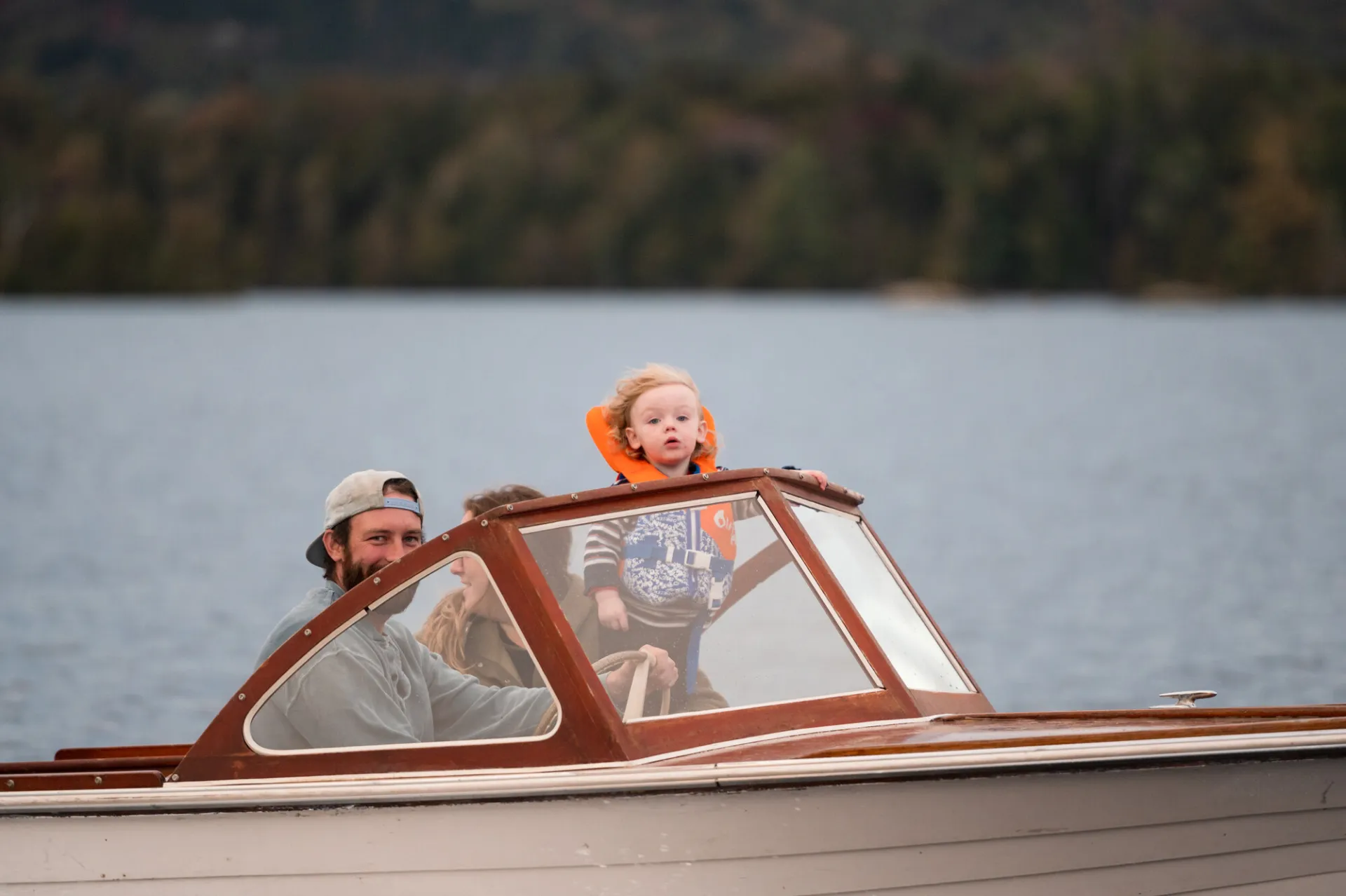A man and his young son look out the front of a boat on a lake. 