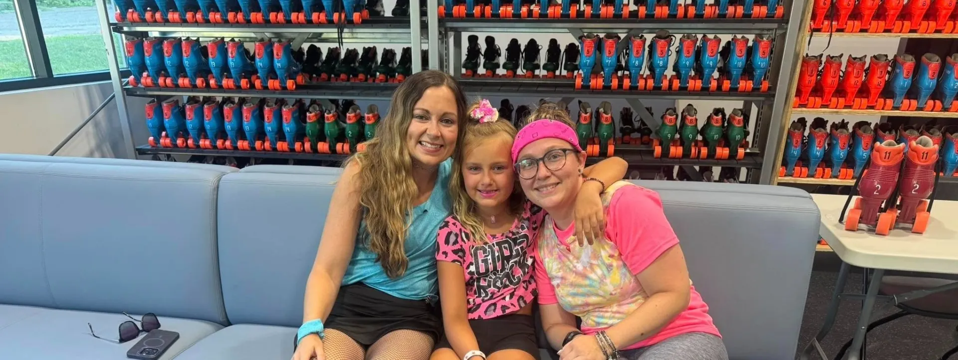Skaters on a bench with a wall of shelves with skates behind them.