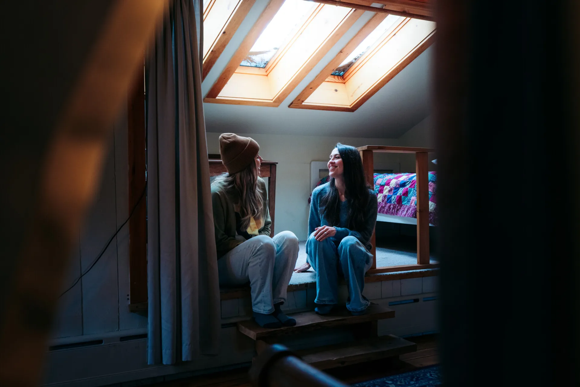 Two women talk in the cove of a cabin.