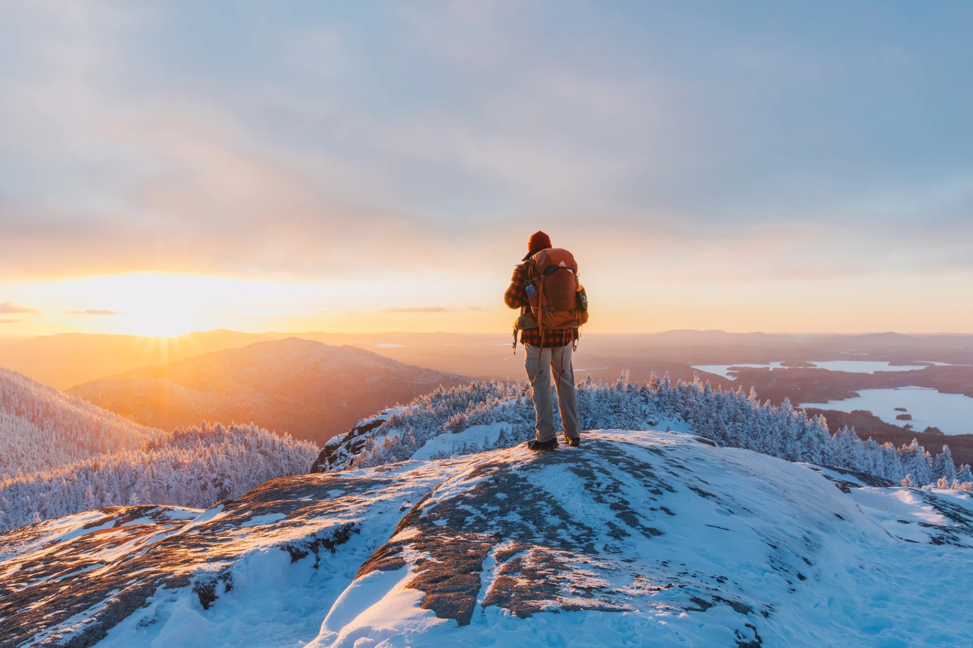 A man stands on top of a snowy mountain top