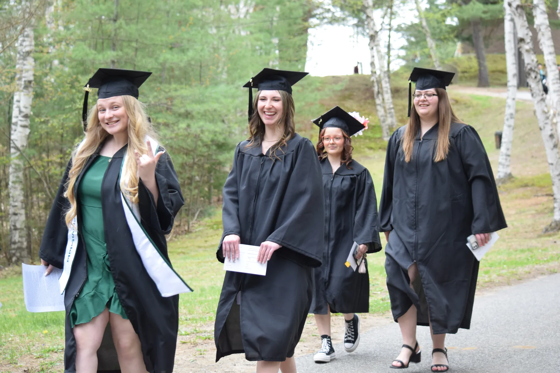 Smiling graduates walk by.