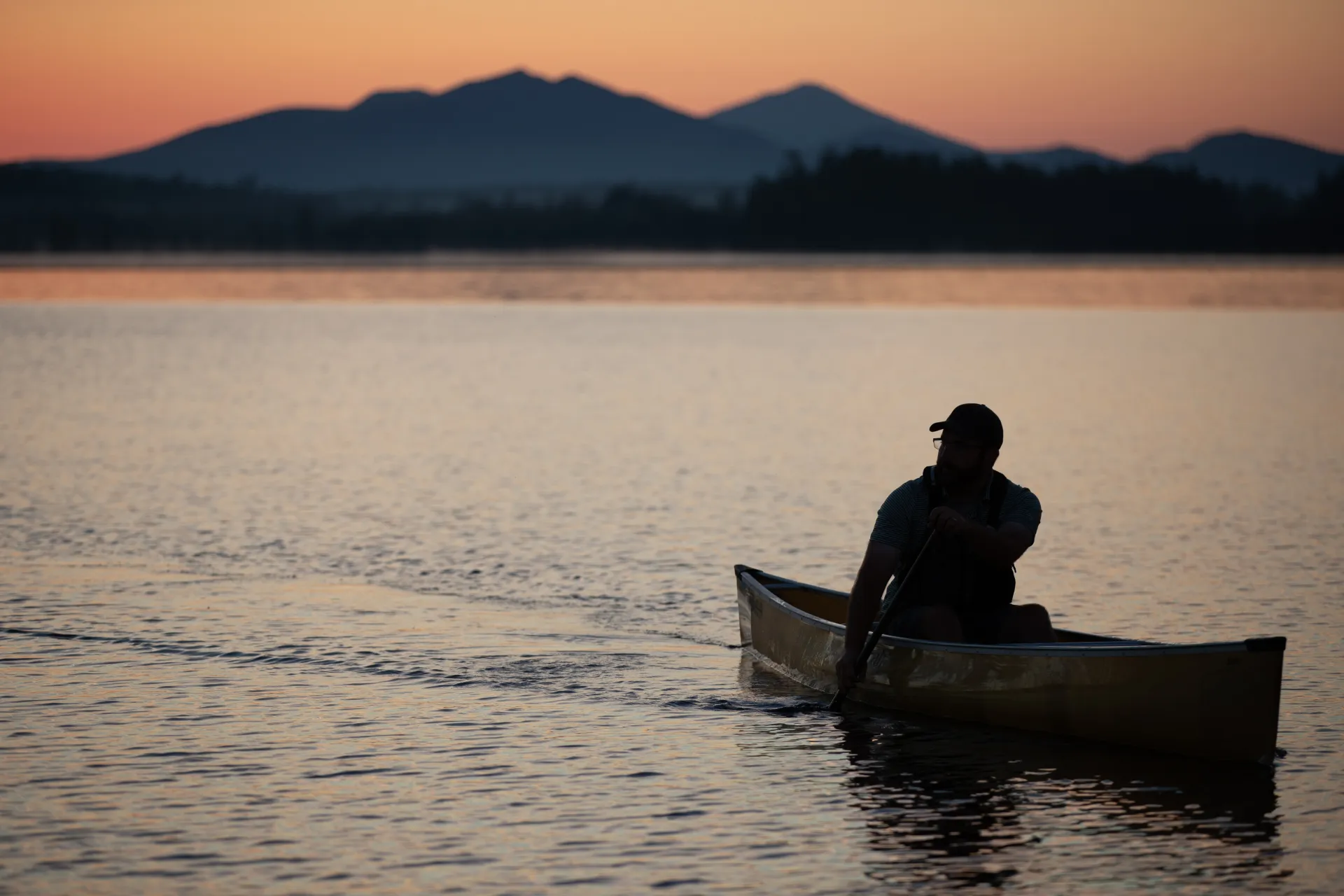 A solo paddler at sunset with the mountains in the back