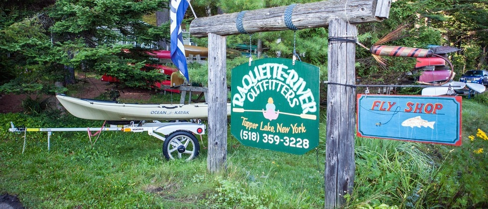 The green sign for Raquette River Outfitters