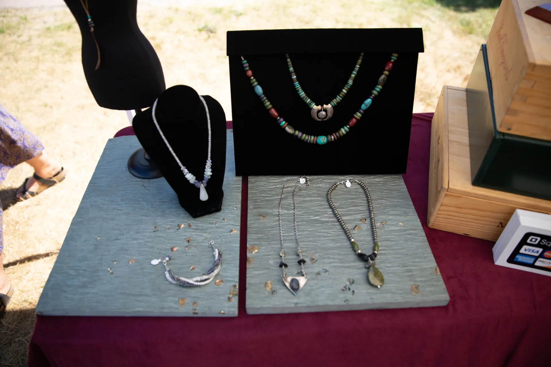 A small display of artisan crafted jewelry on gray and black stands on a table.