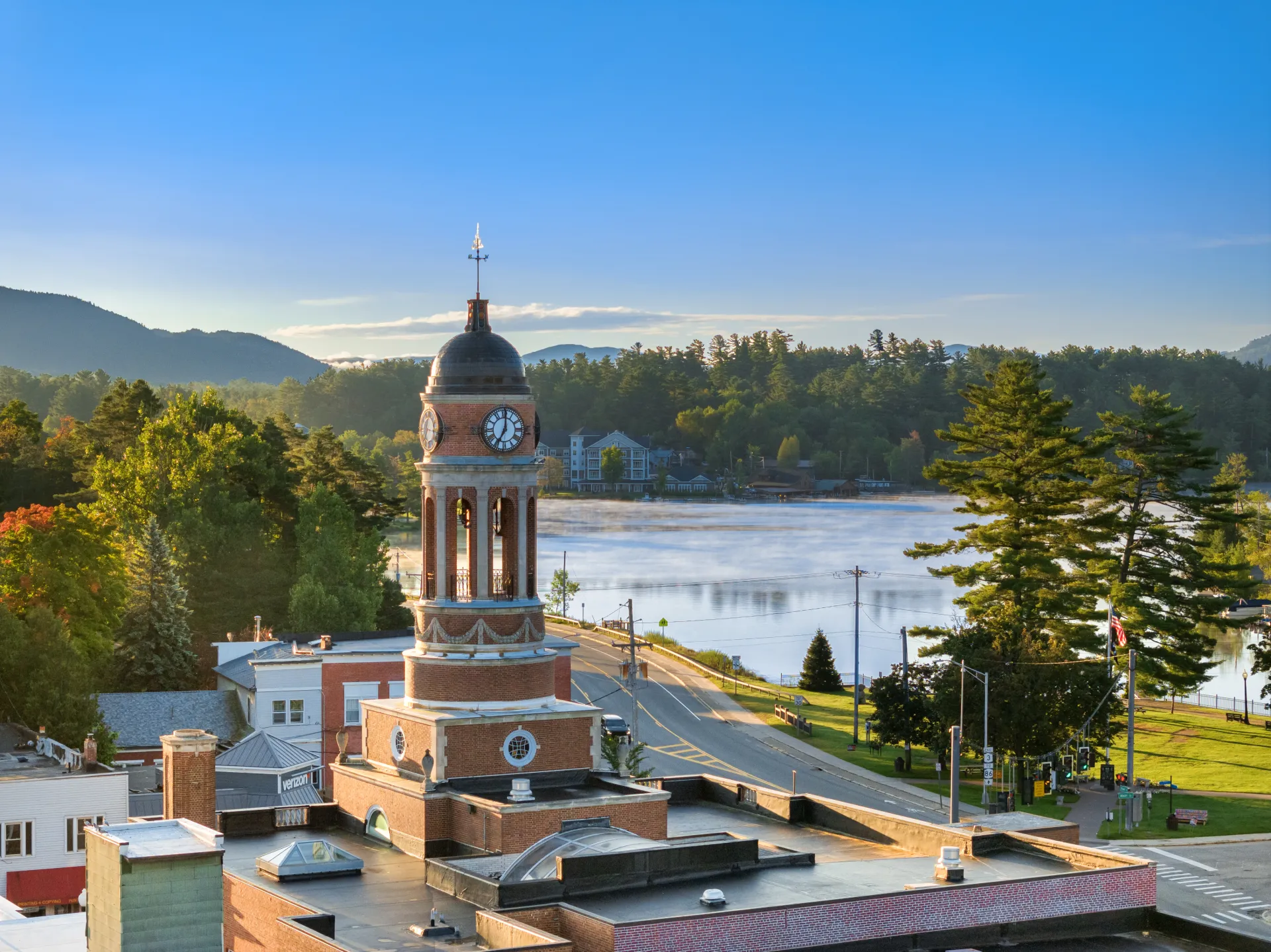 A backed up aerial view of the clock tower at the Harrietstown Town Hall; looking to Lake Flower