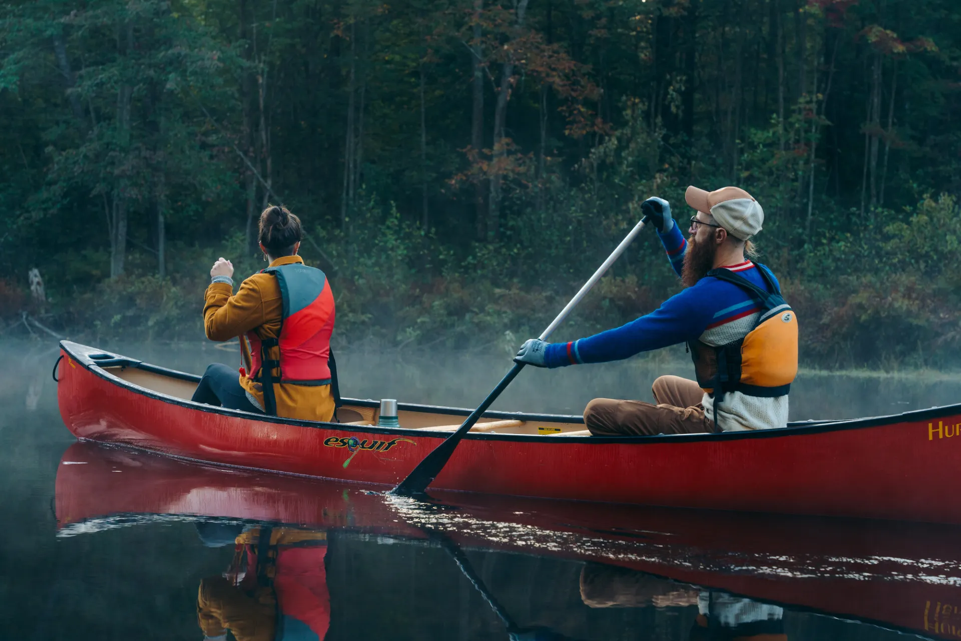 A man and woman paddle a canoe in a river.