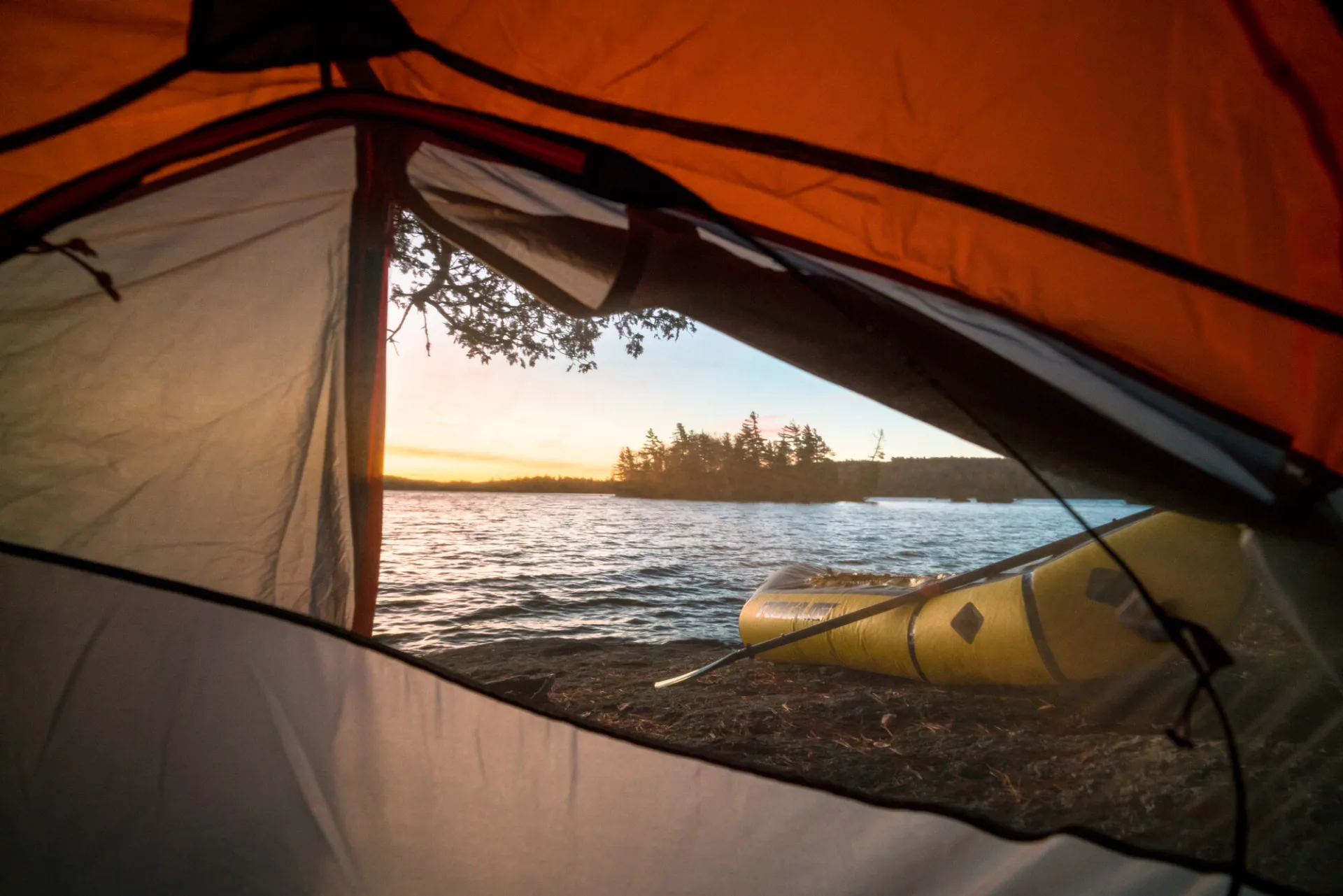 A view of a lake with an island from the entrance of a tent. 