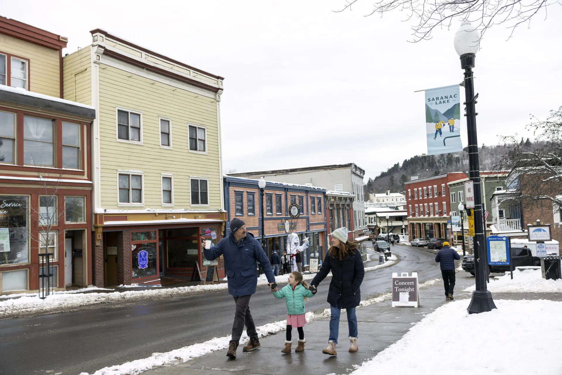 A family of three walks through a town in winter. 