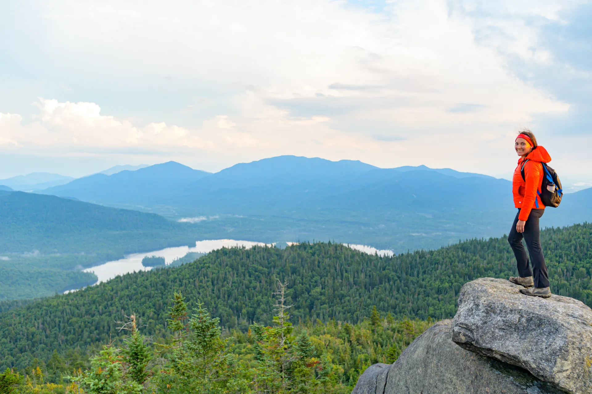 A smiling young woman stares off the top of Ampersand Mountain