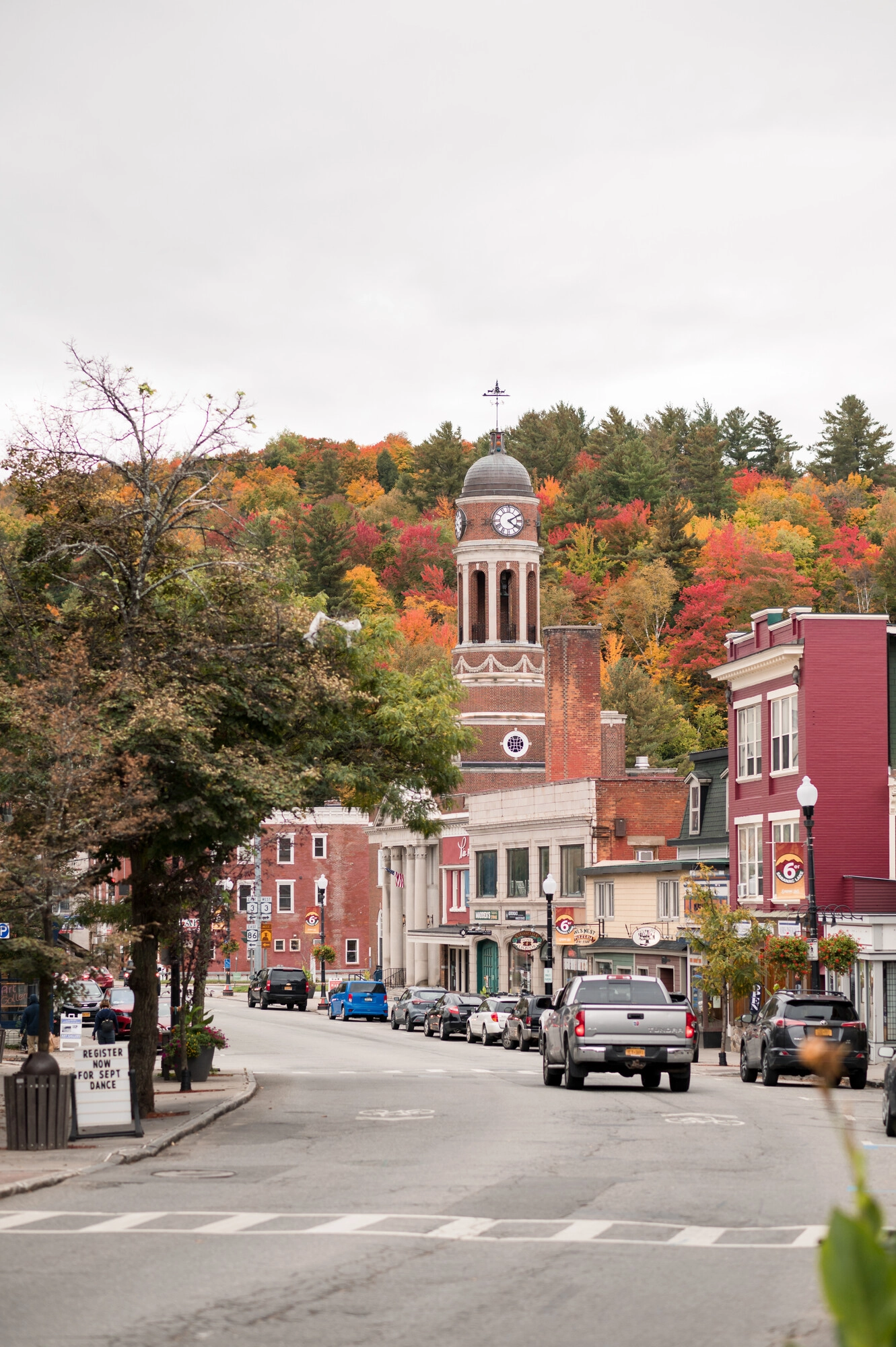 A pickup truck drives through a town in fall. 