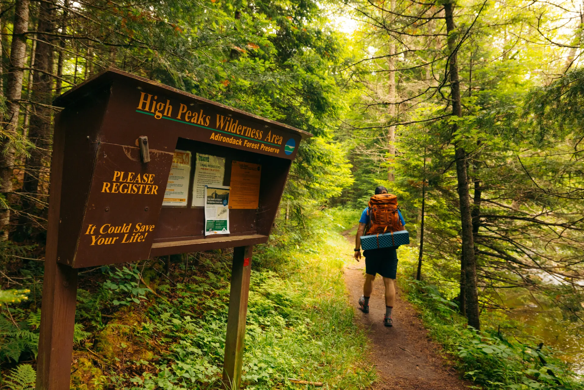 A hiker walking into the woods from the trail register
