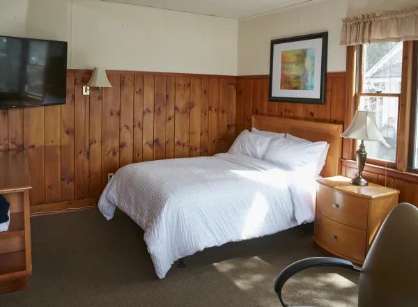 Plush white linens on a queen bed in a wood paneled room at The Ashley.