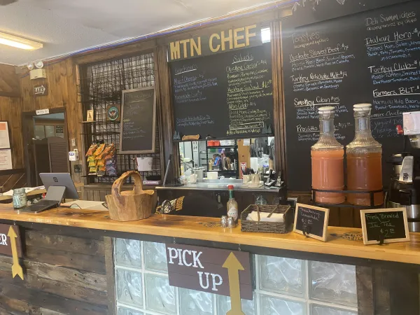 The front counter of Mtn Chef, with drinks on display and hand written chalk board menus