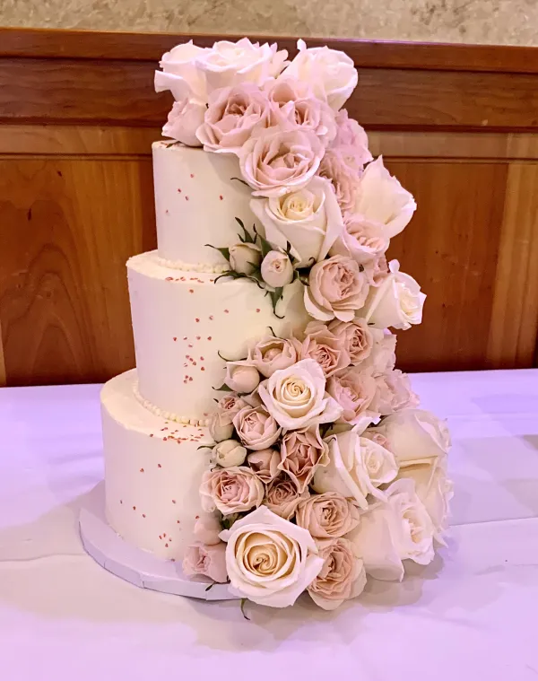 Pink roses flowing down a three tiered cake like a waterfall.