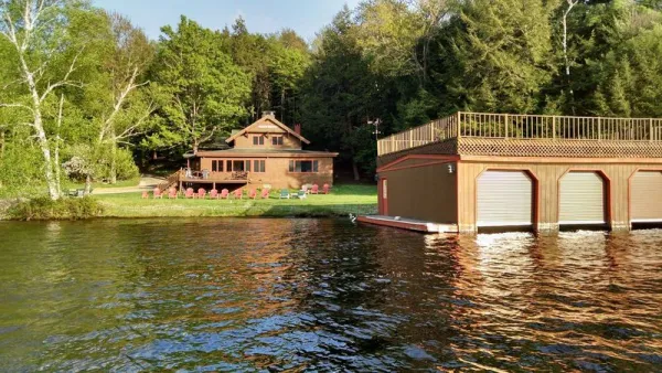 A view from the lake, of the large house, lawn and boathouse with deck.