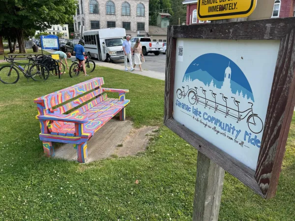 colorfully painted bench beside a community bike ride sign 