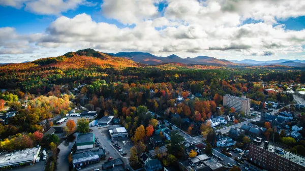 An aerial view of a small town in fall with mountains.