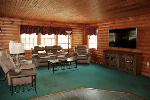 A great room with green carpet and wood paneled walls.