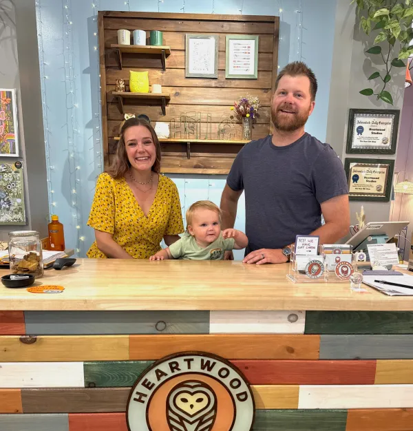 A woman, child and man stand behind the counter at Heartwood Studios