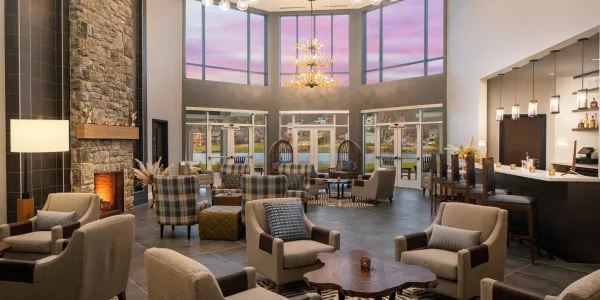 Grand lobby space with stone fireplace, plush armchairs and a view of the lake and mountains