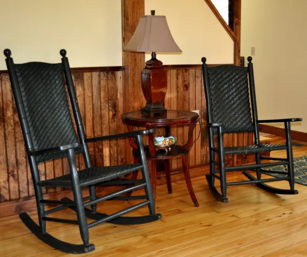 Two black rocking chairs flank a table and lamp.