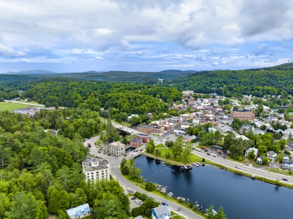 A backed up aerial view of the clock tower at the Harrietstown Town Hall and proximity to Lake Flower