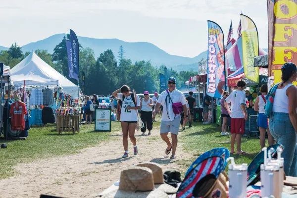 People walk down roadway flanked by vendors at Lacrosse tournament in Lake Placid