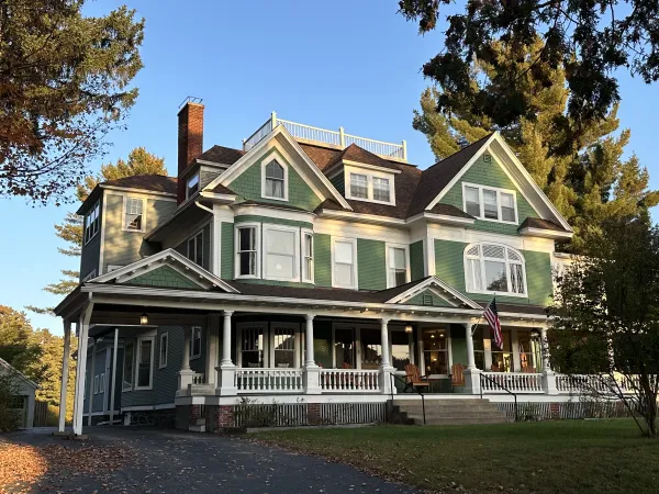 Exterior of the Franklin Manor with elaborate white trim, multiple rooflines and a large covered veranda and widows walk on the roof.