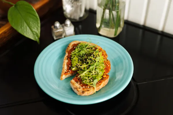 Avocado toast with sprouts on a colorful plate.