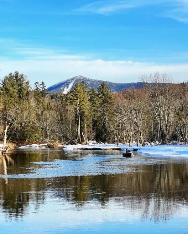 A view of a snow covered slide on a mountain from the water.