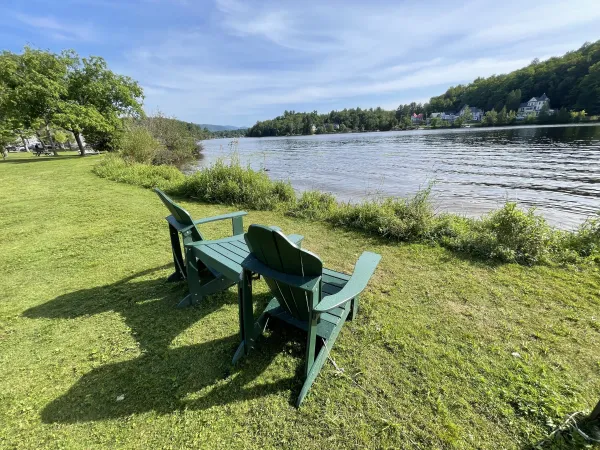two adirondack chairs on the edge of a lake