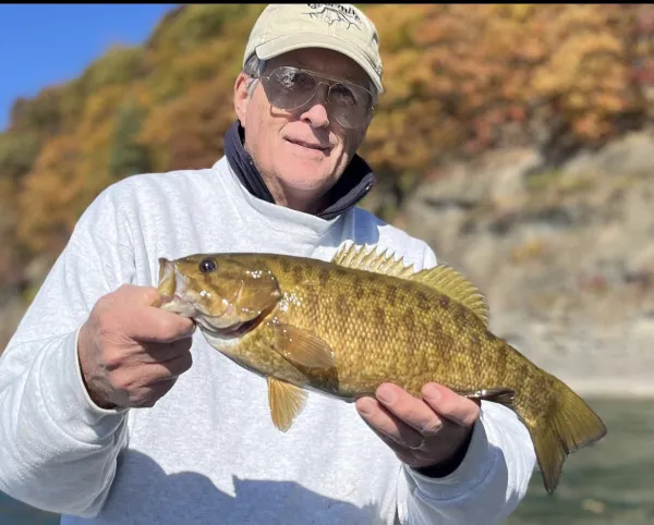 A smiling older gentleman holds a fish.