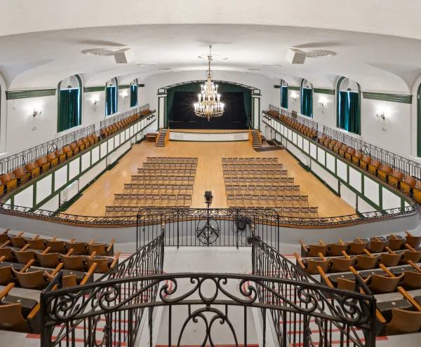 The auditorium with balconies and raised, curtained stage at the Harrietstown Town Hall, viewed from the balcony